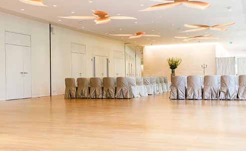 Ein geräumiger, eleganter Festsaal mit überdachten Stuhlreihen und hellem Holzfußboden - perfekt für Veranstaltungen mit Catering in der Flora Köln.