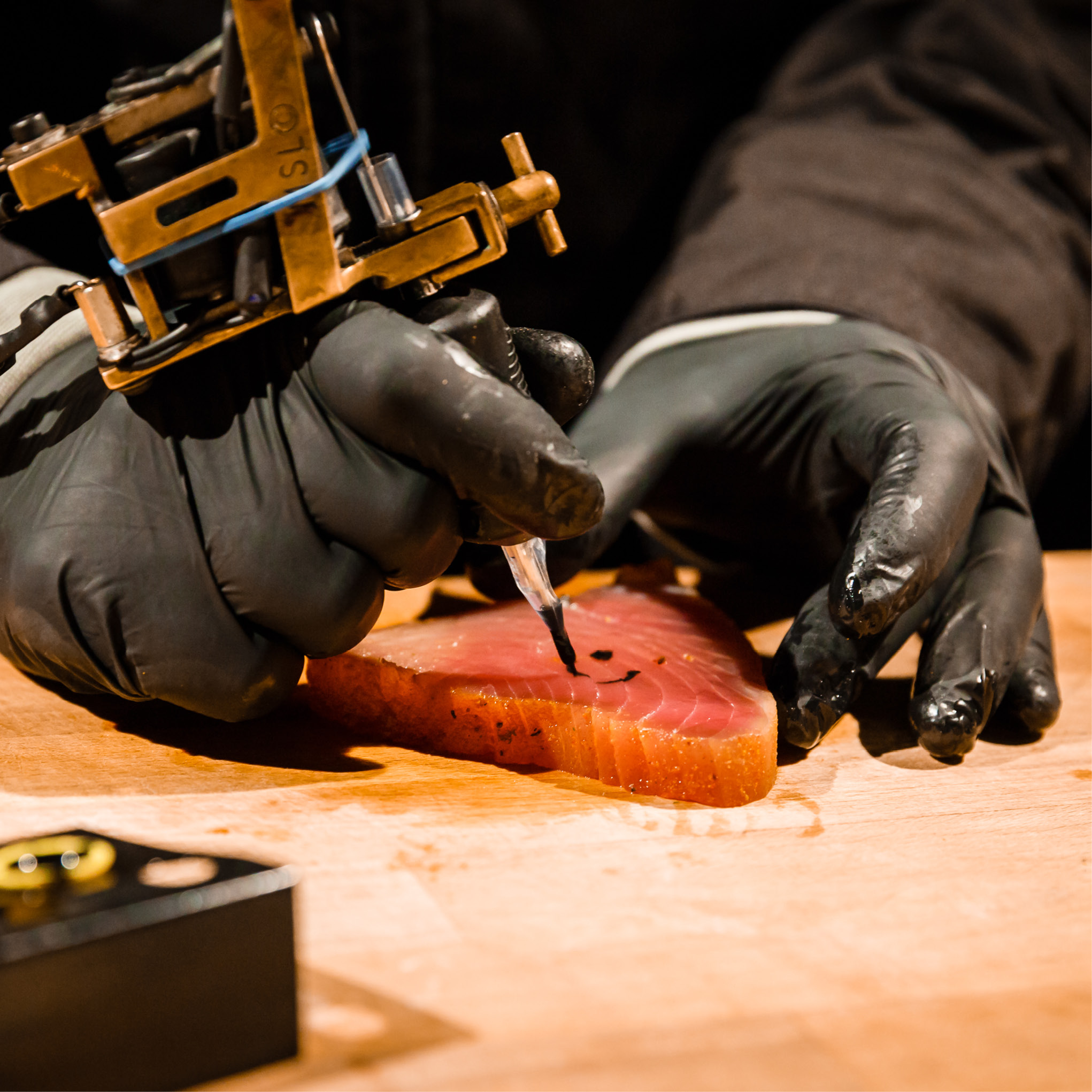 Eine Person mit schwarzen Handschuhen tätowiert eine Scheibe rohen Fisch auf eine Holzoberfläche.