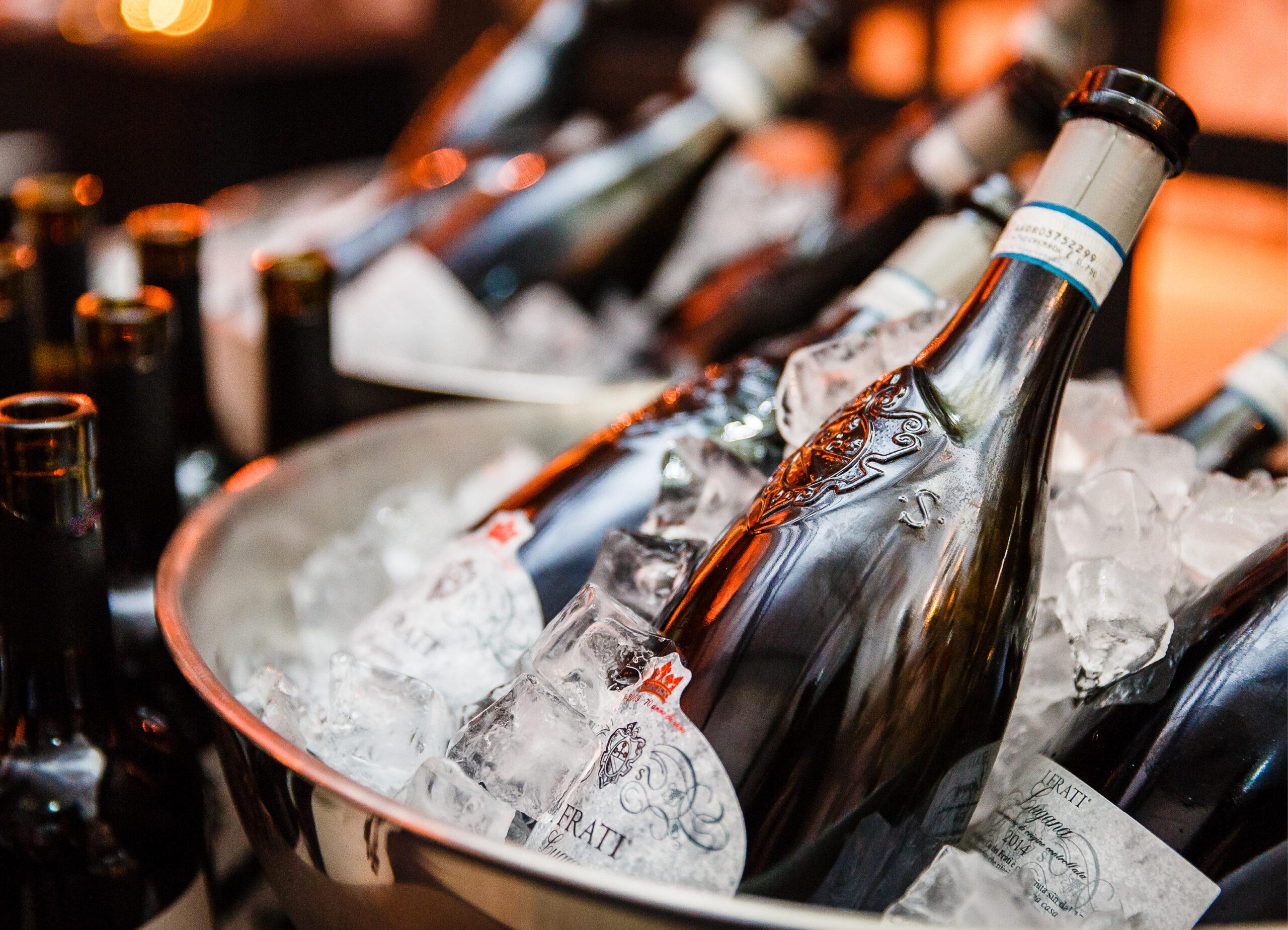 Sektflaschen kühlen in einem Eiskübel, umgeben von anderen Weinflaschen - perfekt für Ihr nächstes Fine Dining Catering in Köln.