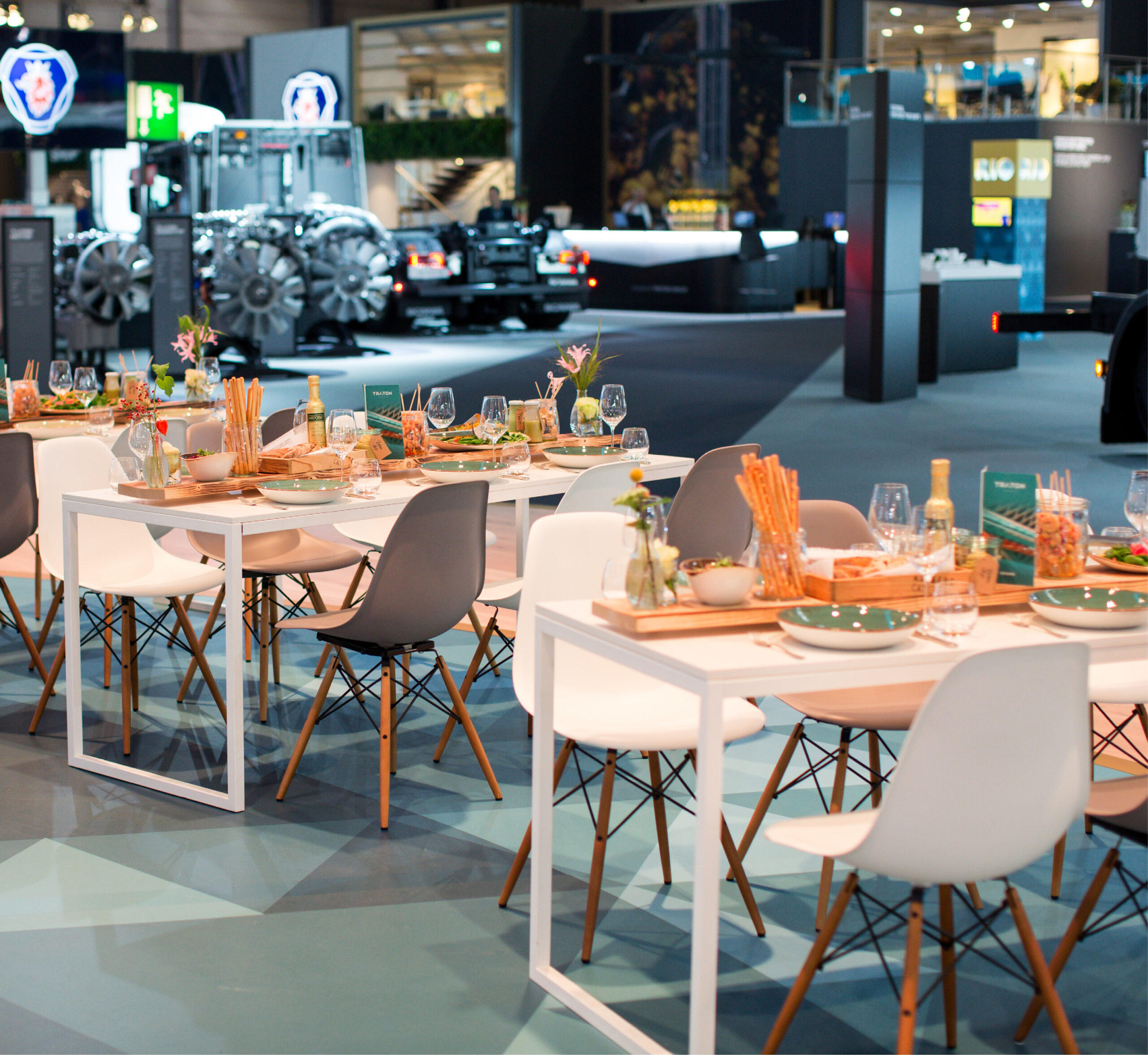 Moderne Esstische für eine Mahlzeit in einem offenen, industriell gestalteten Veranstaltungs- oder Ausstellungsraum - ideal für das Messecatering für Veranstaltungen.