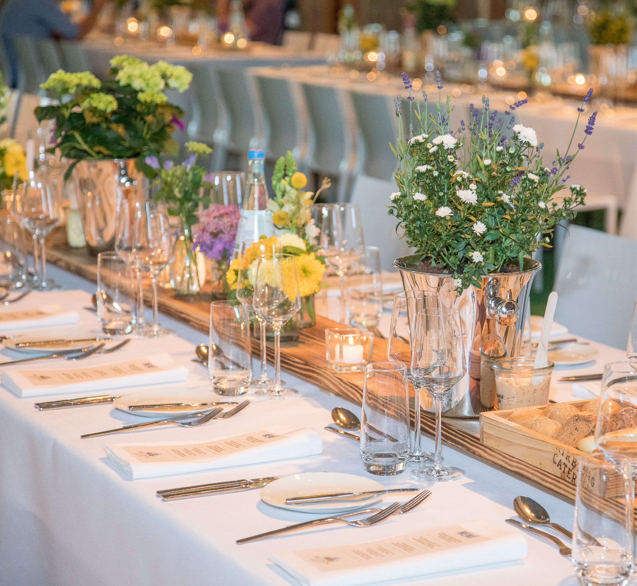 Eleganter gedeckter Tisch mit Blumen, Menüs, Gläsern und Brotkörben für eine formelle Veranstaltung oder ein Abendessen - perfekt für hochwertiges Messecatering für Veranstaltungen.