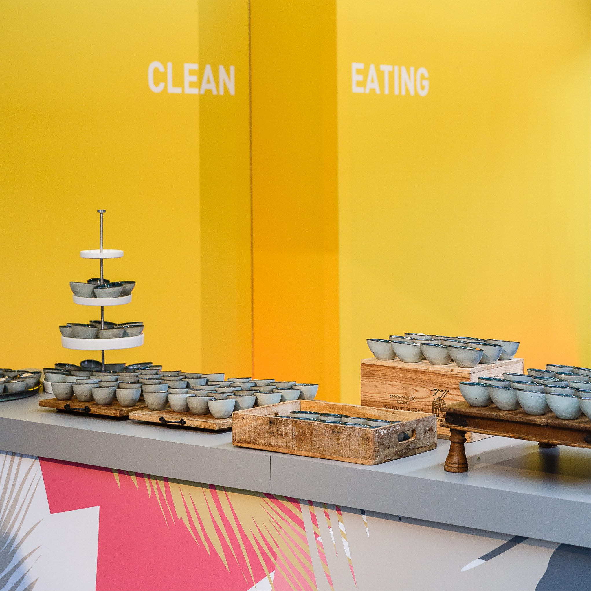 Ein Tresen mit gestapelten Schüsseln vor einer gelben Wand mit der Aufschrift CLEAN EATING, perfekt für Catering für Tagungen und Konferenzen.