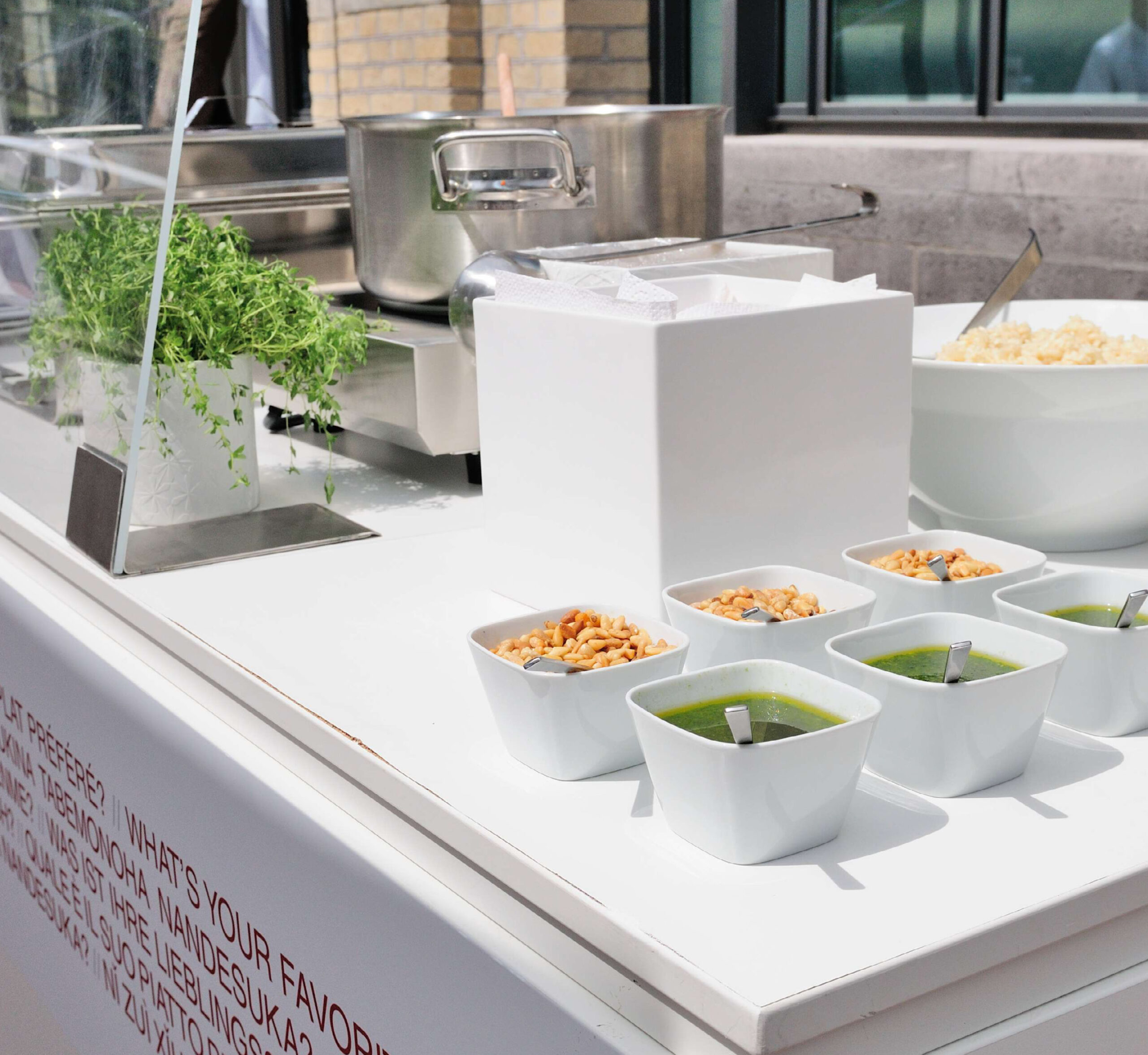 Weißer Tresen mit Schalen mit grüner Soße, knusprigen Toppings, frischen Kräutern und einem Topf im Hintergrund - die perfekte Inspiration für Catering für Tagungen und Konferenzen.