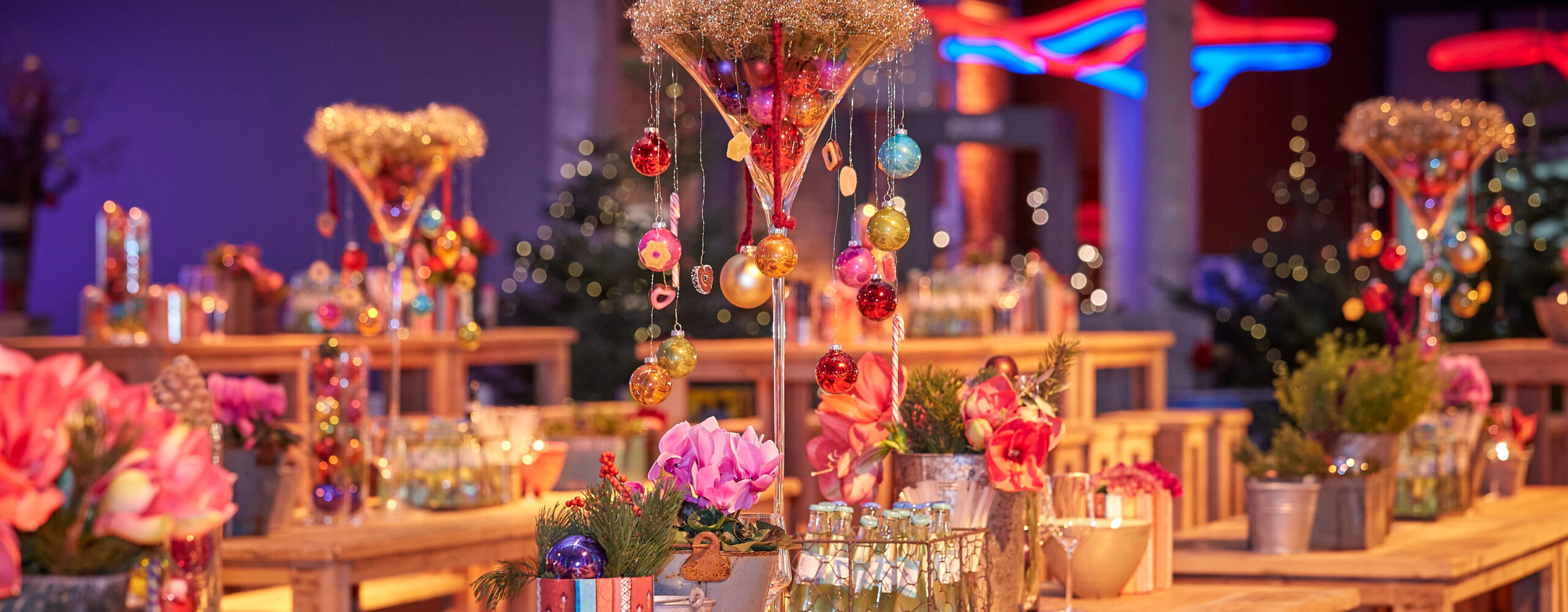 Festliche Partytische mit Blumen, Getränken und bunten Ornamenten in einem warmen, lebendigen Ambiente - perfekt für Weihnachtsfeiern Catering in Köln.