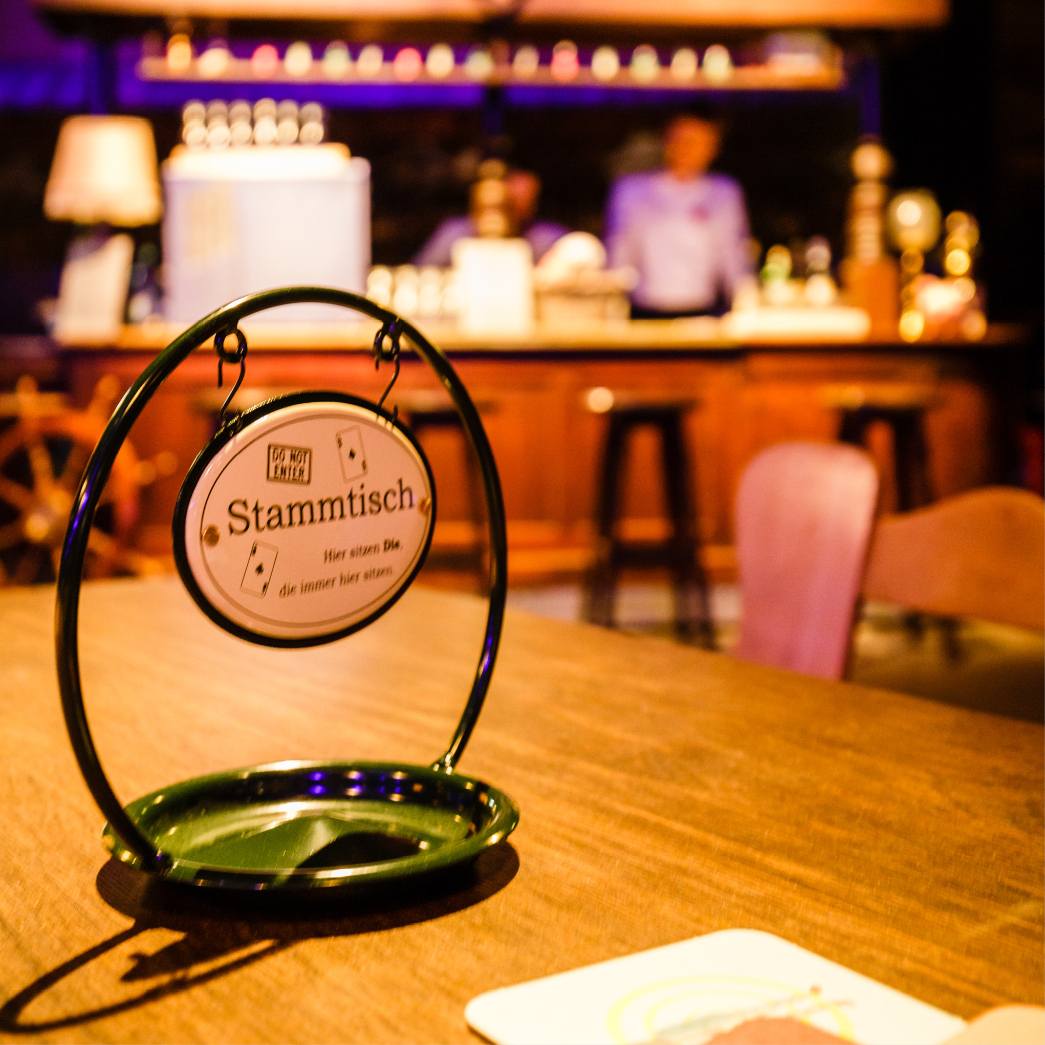 Ein reserviertes Stammtischschild steht auf einem Holztisch in einer warm beleuchteten Bar, perfekt für das Weihnachtsfeiern Catering in Köln.