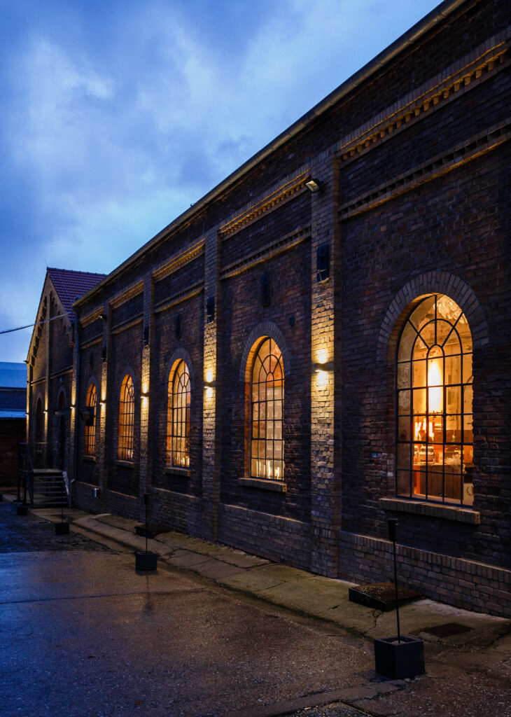 Ein Backsteingebäude mit gewölbten Fenstern, das in der Abenddämmerung bei bewölktem Himmel warm beleuchtet ist - ein einladender Ort.