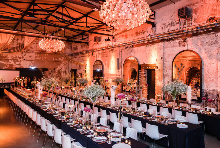 Eleganter Bankettsaal von Harbour Club Events und Catering mit langen Esstischen, floralen Tischdekorationen und Kronleuchtern unter warmer Beleuchtung.