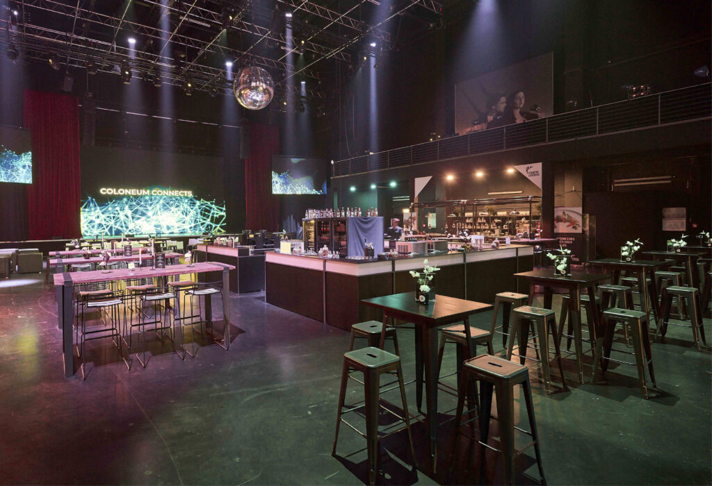 Großzügiger moderner Veranstaltungsort, Studio 50 als Eventlocation, mit Stehtischen, Hockern, einem Barbereich und einer großen Leinwand mit COLOSSEUM CONNECTS.