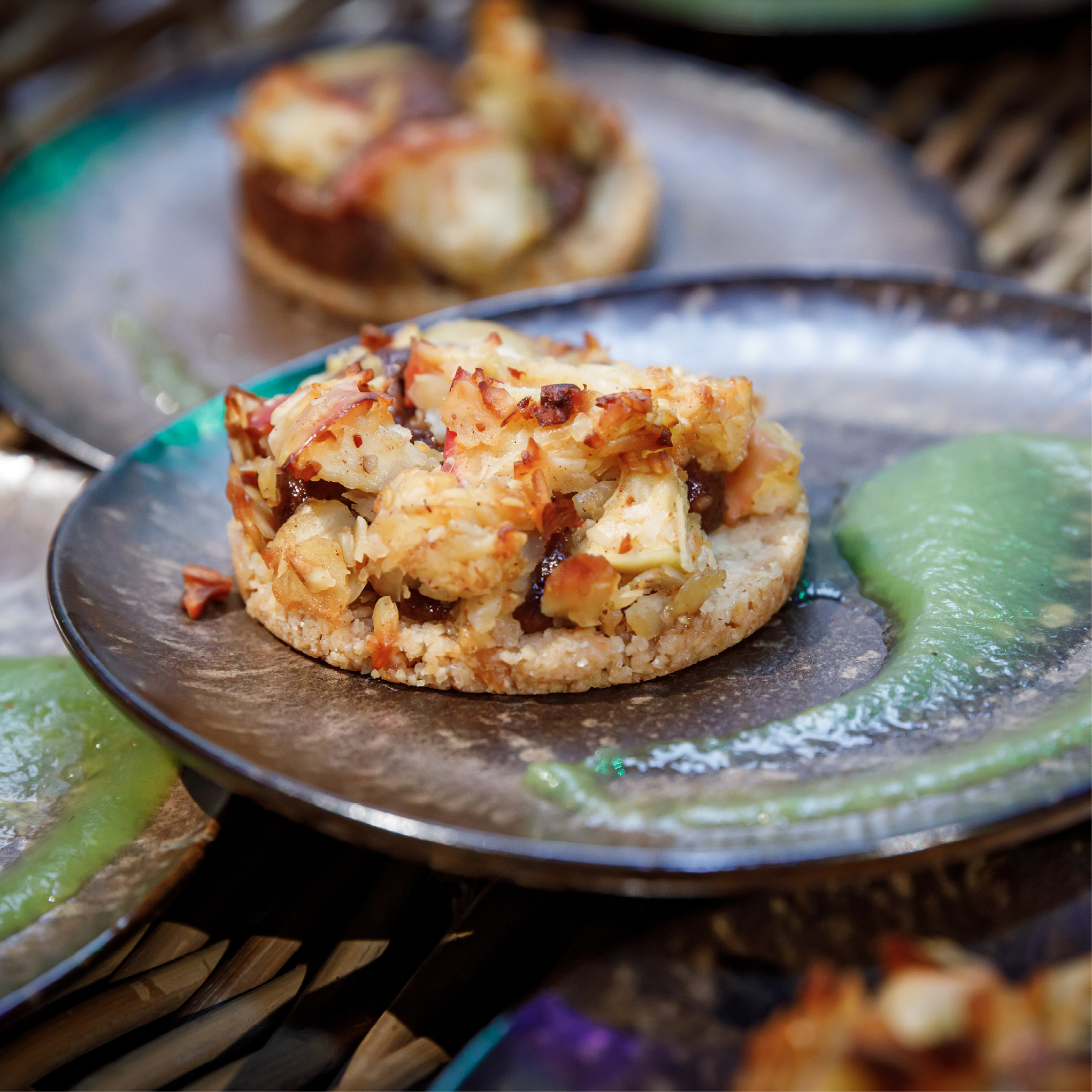 Eine herzhafte Torte auf einem Teller mit grüner Soße daneben.