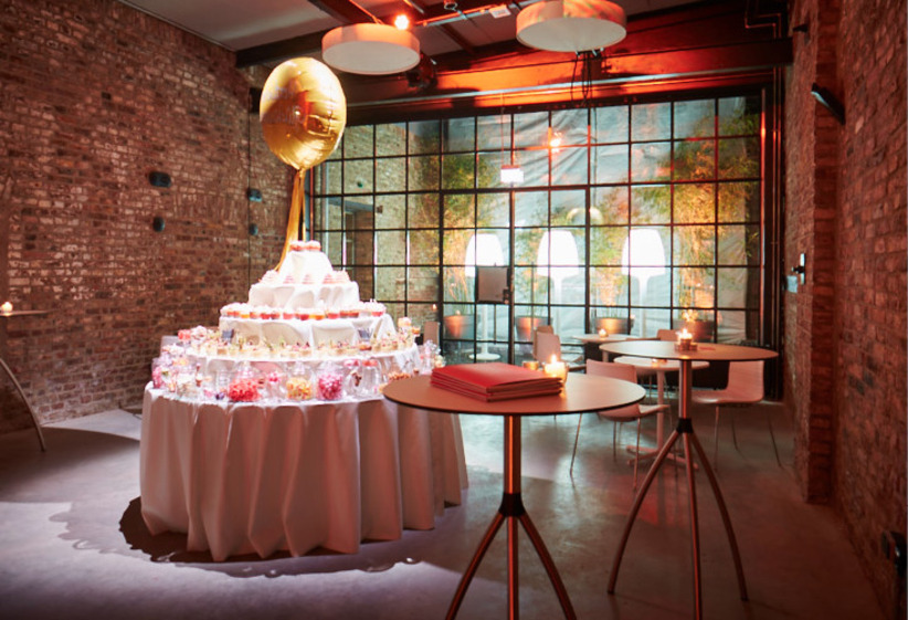 Ein mehrstufiger Desserttisch mit einem großen goldenen Ballon in einem modernen Veranstaltungsraum im Industriestil von Harbour Club Events und Catering.