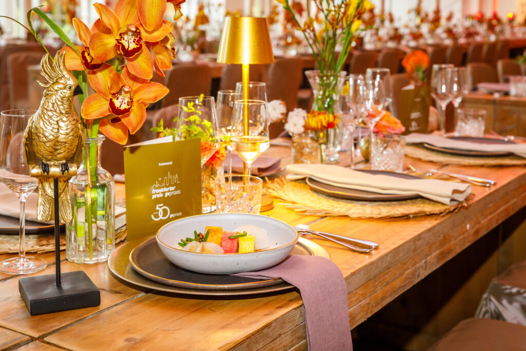 Detailreich gedeckte Tafel für eine gehobene Abendveranstaltung, mit goldenen Akzenten, Orchideen und stilvollem Besteck.