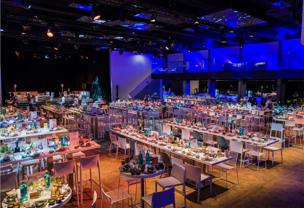 Geräumiger Bankettsaal mit moderner Einrichtung, gedeckten Tischen und blauer Beleuchtung – ideal für ein formelles Abendessen oder eine Veranstaltung. Perfekt, wenn Sie Eventlocations Köln mieten möchten.