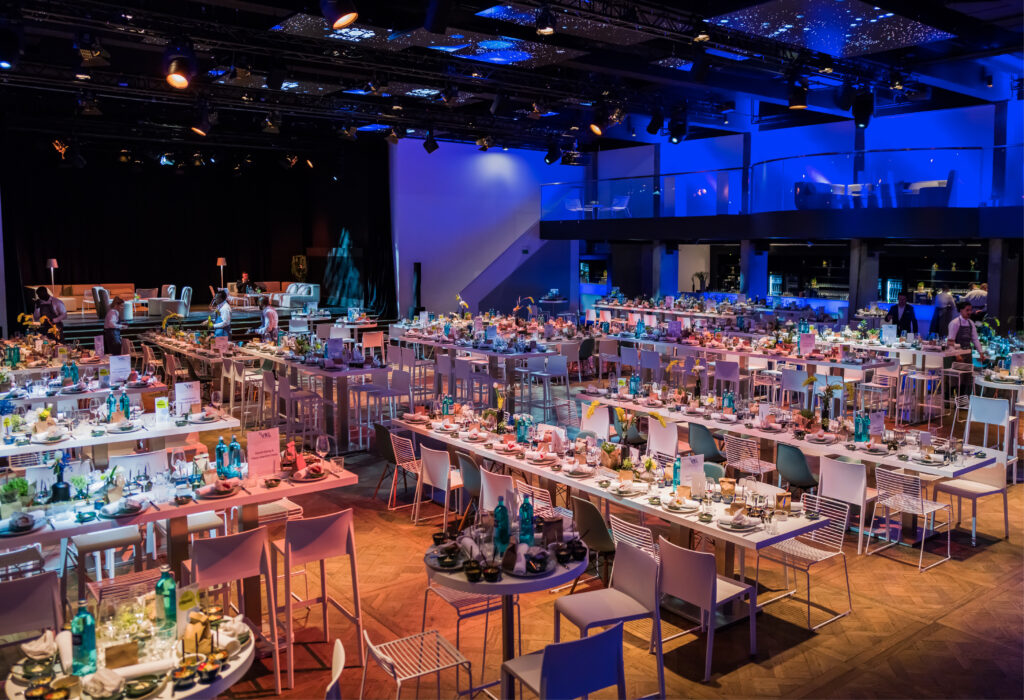 Palais Frankfurt - Großer Bankettsaal mit langen, für eine Veranstaltung gedeckten Tischen, dekoriert mit Blumen und blauer Beleuchtung.