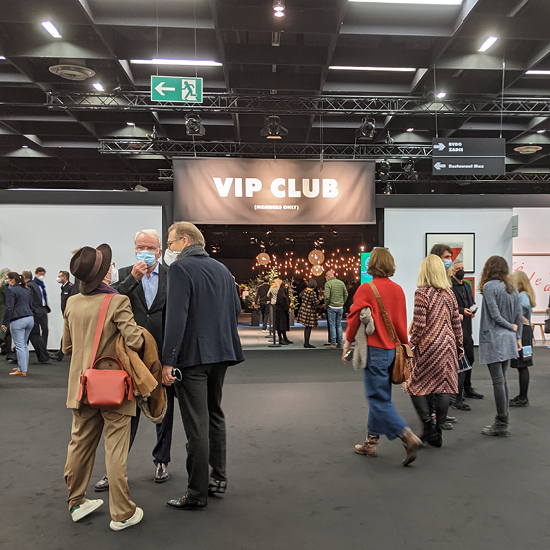 Menschen stehen und unterhalten sich in der Nähe des Eingangs zu einem VIP-Club bei einer Indoor-Veranstaltung.