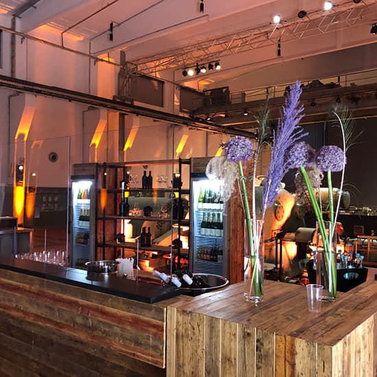 Eine stilvolle Bar mit Holztheken, Blumen in Vasen und warmer Atmosphäre in einem modernen Lokal.