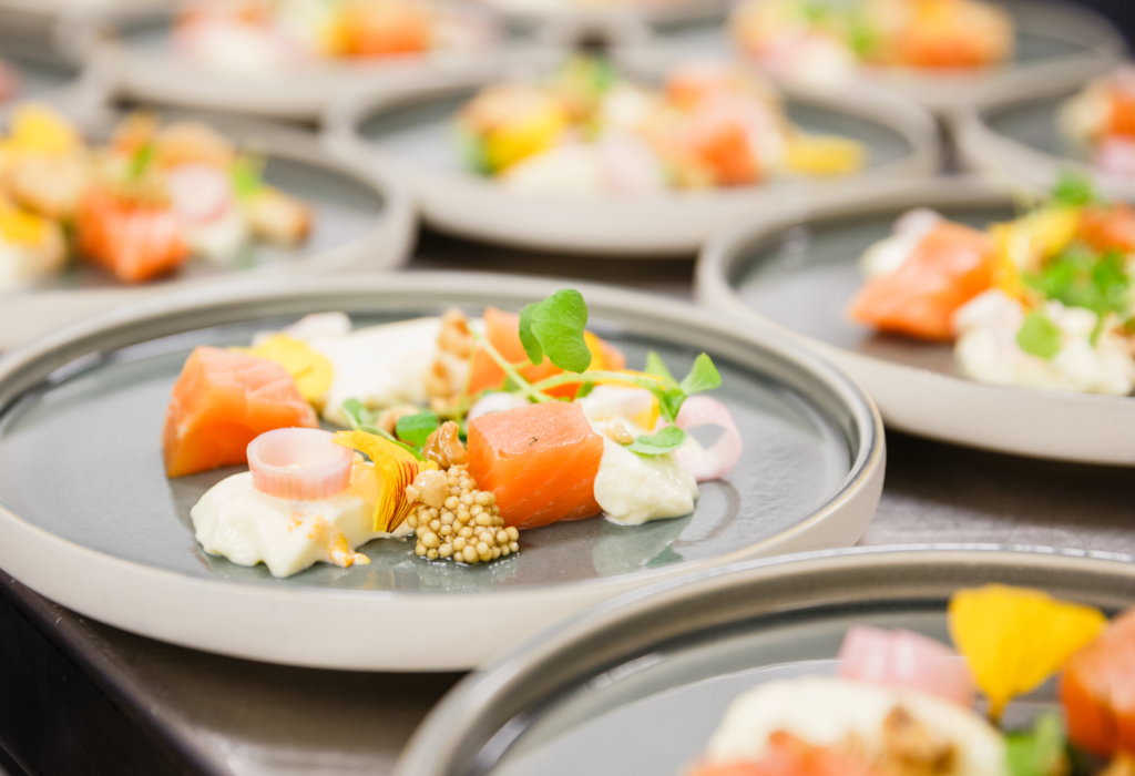Hochwertige Speise mit Lachs, kunstvoll auf Tellern angerichtet.
