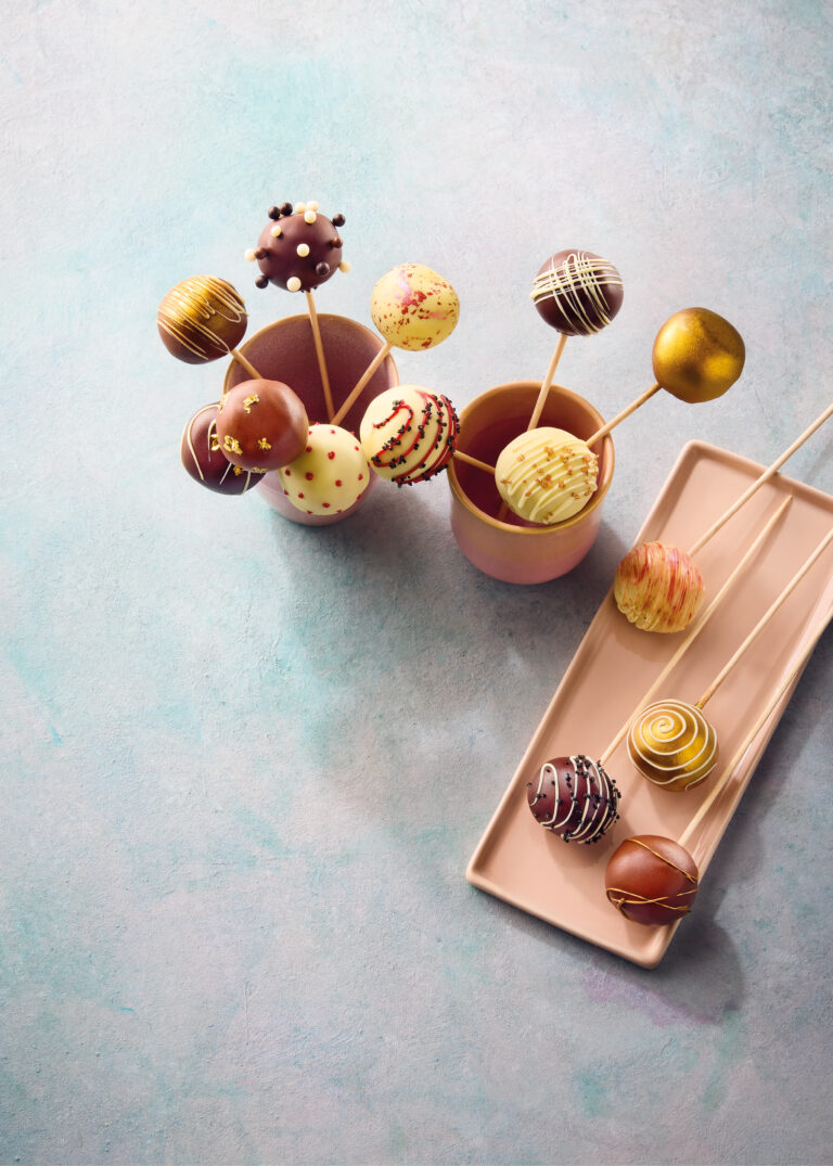 Verzierte Cake-Pops in verschiedenen Schokoladenarten, mit goldenen und roten Mustern, aus einem exklusiven Profirezept