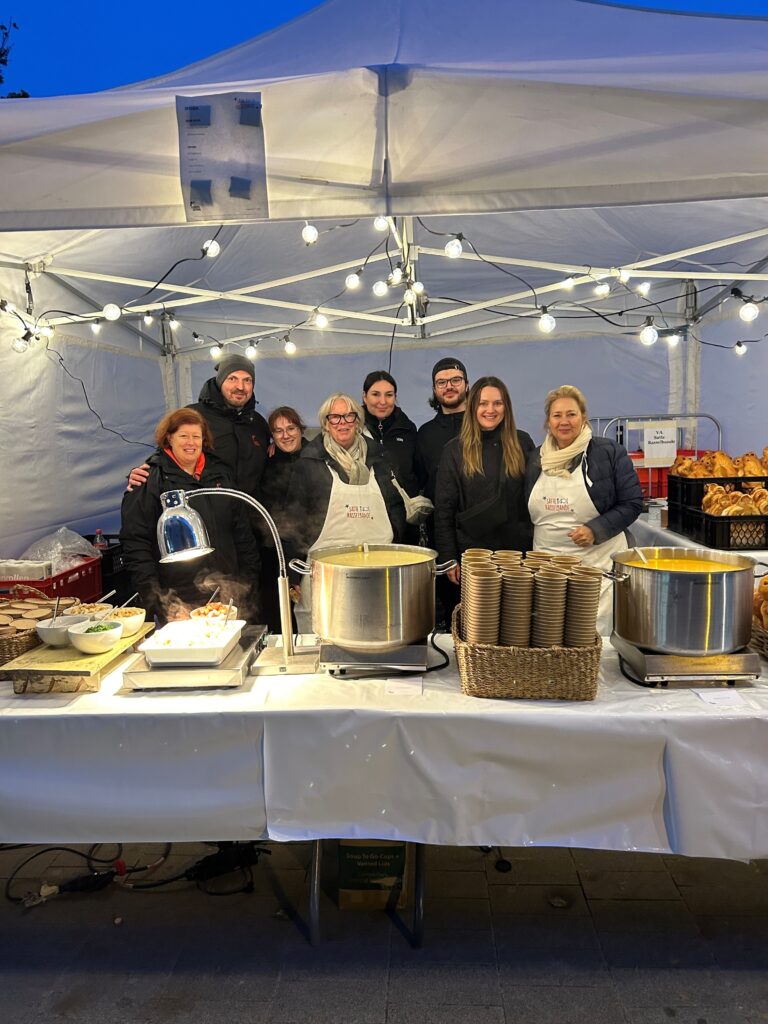 Bild von Kirberg-Mitarbeitern, die ehrenamtlich Essen für bedürftige Familien beim Martinszug der Satten Rasselbande ausgeben.