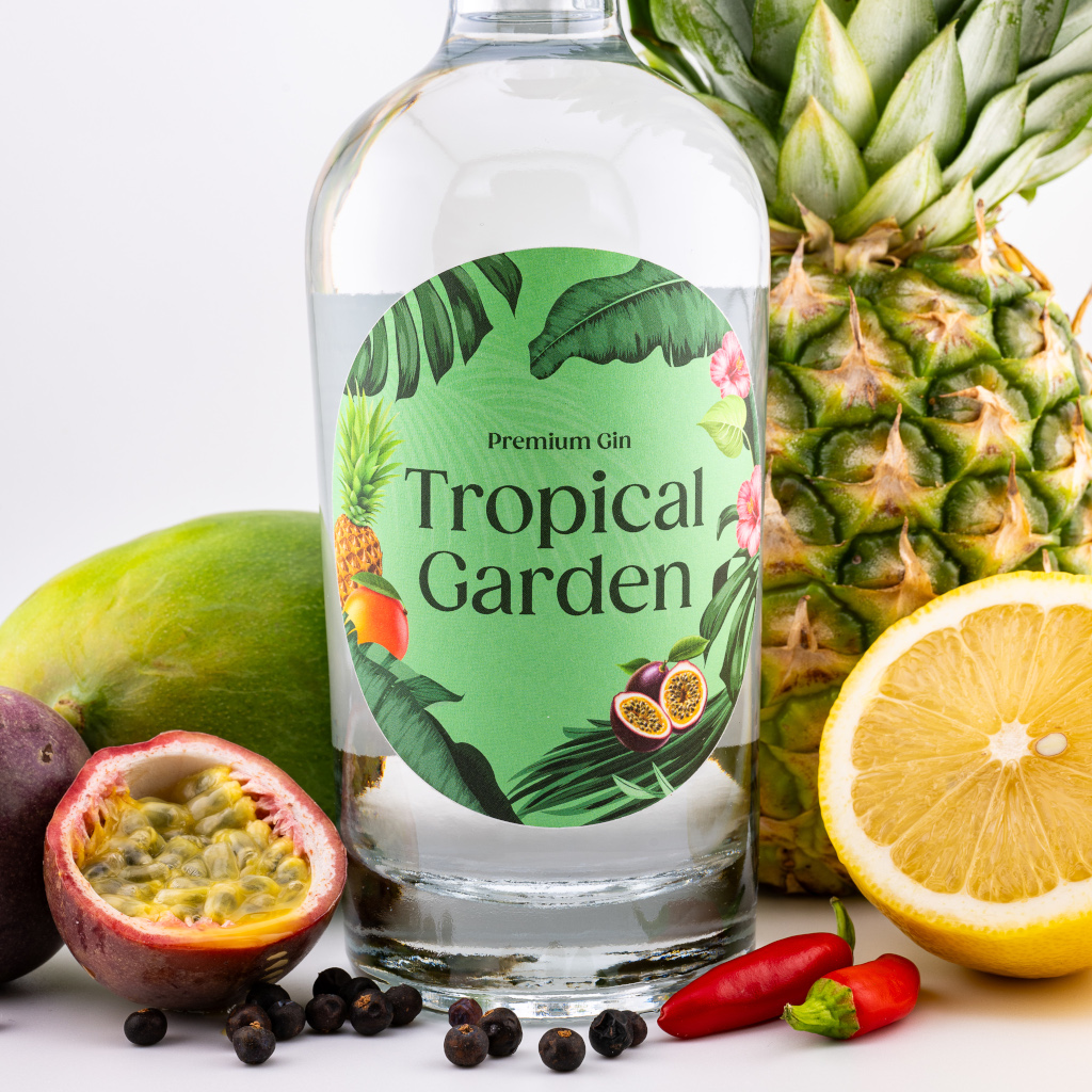 Tropical Garden Gin: Produktfoto mit Flasche zwischen frischen tropischen Früchten wie Maracuja, Ananas und Mango.