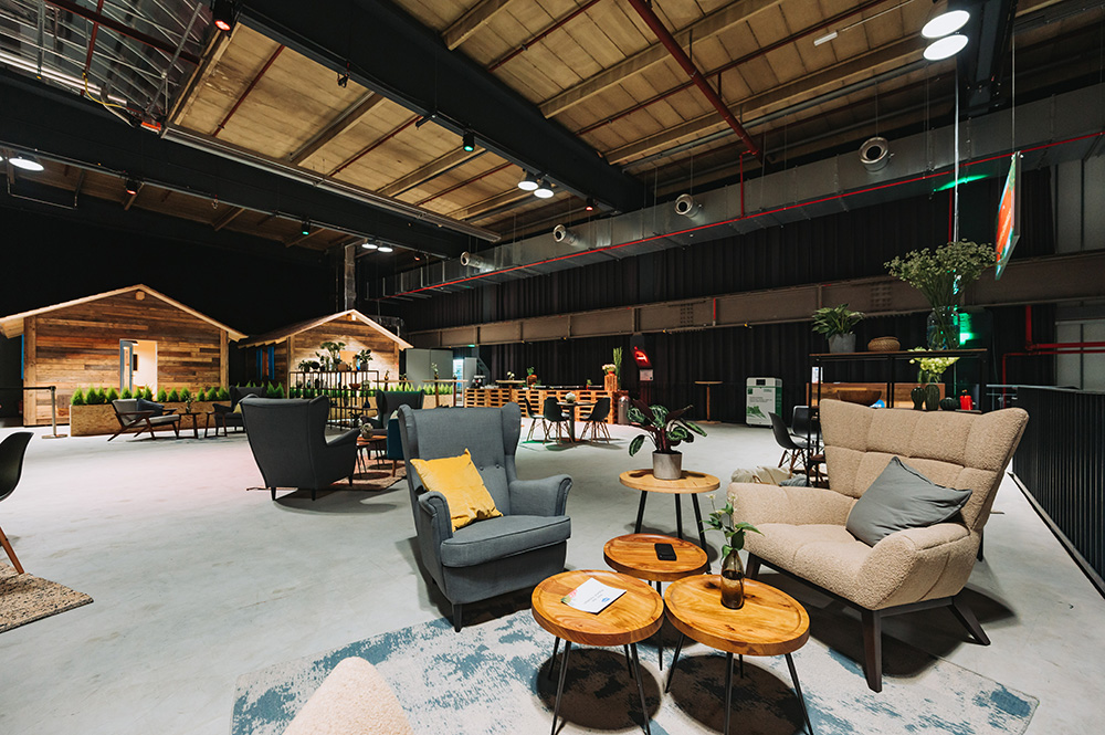 Geräumige, moderne Lounge mit gemütlichen Sitzgelegenheiten, Holztischen und Dekoration im Kabinenstil in einer industriellen Umgebung.