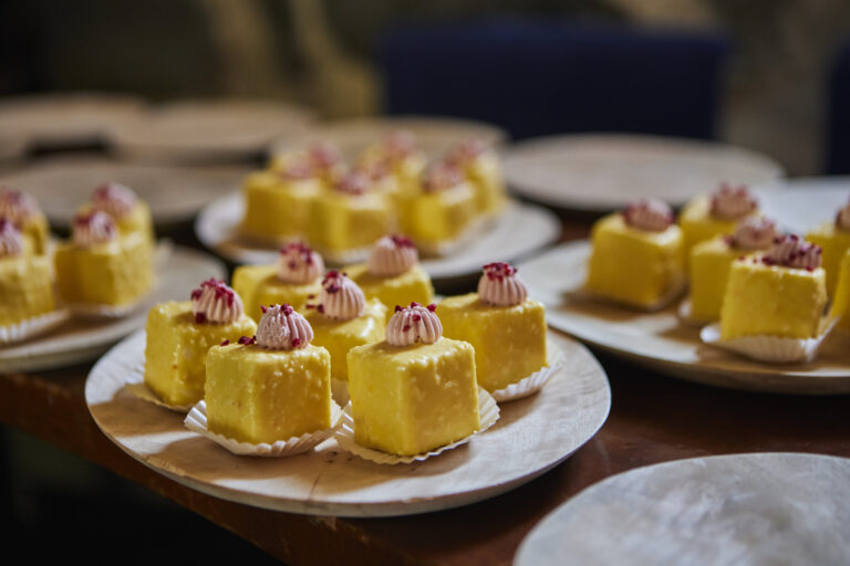 Gelbe Dessertwürfel mit Creme-Topping und roten Verzierungen als hochwertiges Fingerfood für ein Kirberg Eventcatering.